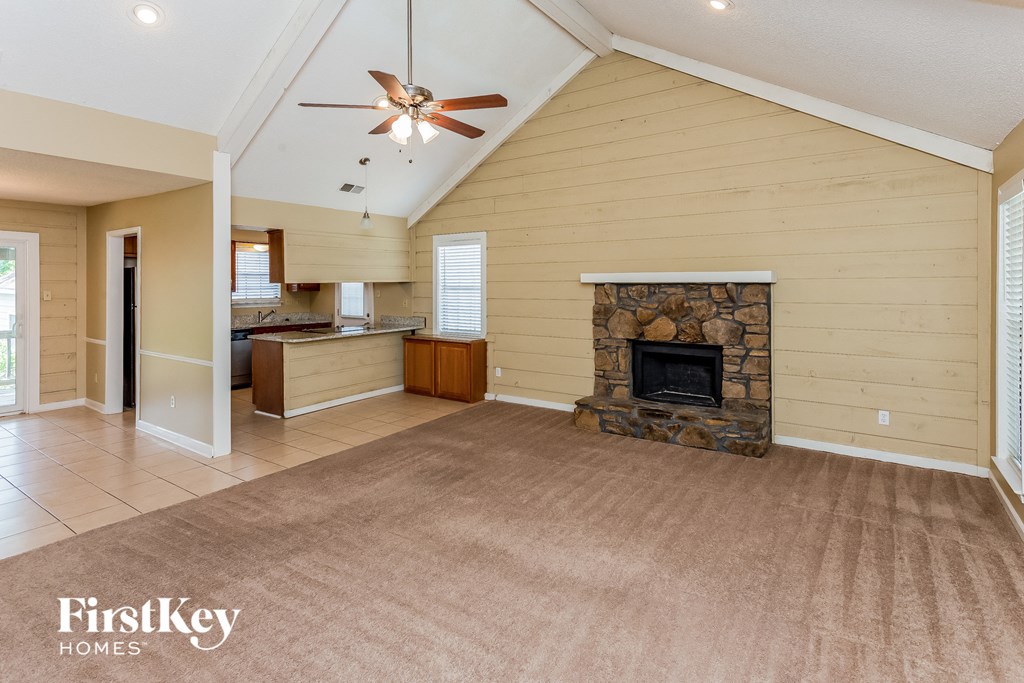 A spacious living room with a fireplace and a ceiling fan.