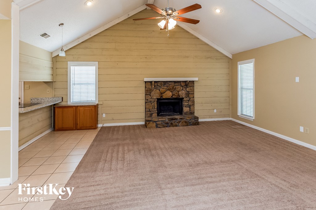 A spacious living room with a fireplace and a ceiling fan.