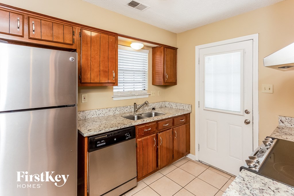 A kitchen with a stainless steel refrigerator and wooden cabinets.