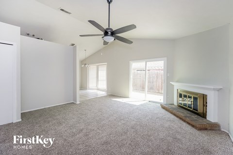 an empty living room with a fireplace and a ceiling fan