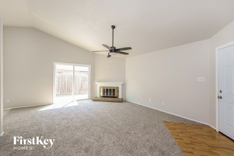 an empty living room with a ceiling fan and a fireplace