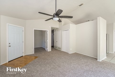 a living room with white walls and a ceiling fan