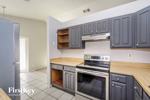 a kitchen with gray cabinets and stainless steel appliances and wooden counter tops