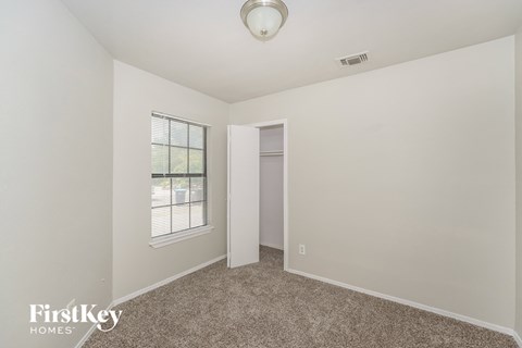a bedroom with white walls and carpet and a door to a closet