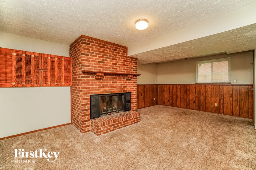 a living room with a brick fireplace and a carpeted floor