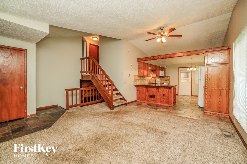 a kitchen and living room with a carpeted floor and a ceiling fan