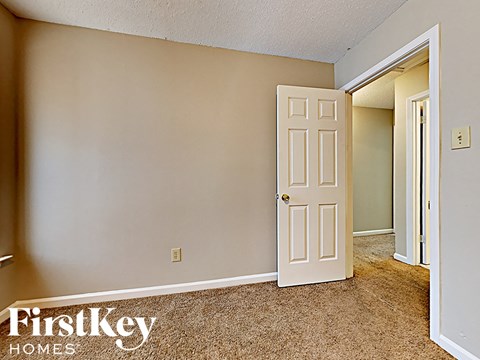 A room with a white door and a carpeted floor.