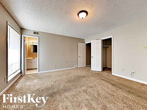 A room with a carpet floor and a FirstKey Homes logo.