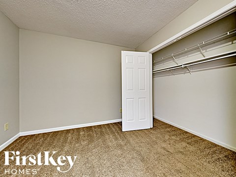 A room with a white door and a carpeted floor.