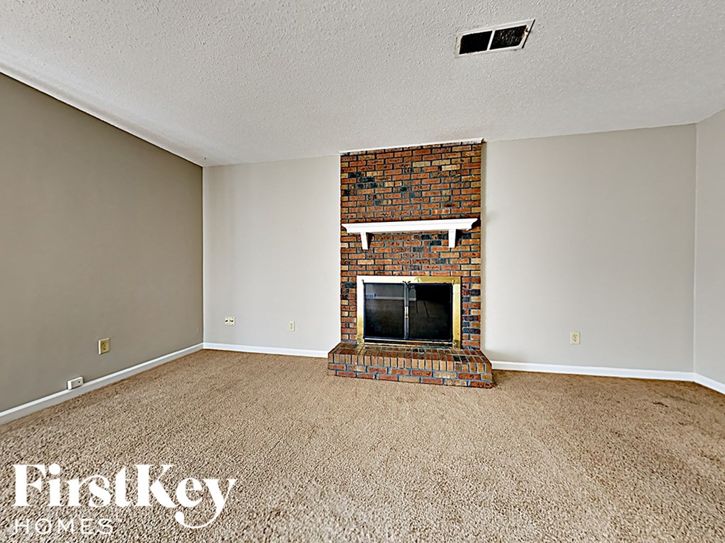 A room with a fireplace and carpeting.