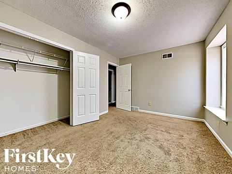 A bedroom with a carpeted floor and a closet with a white door.