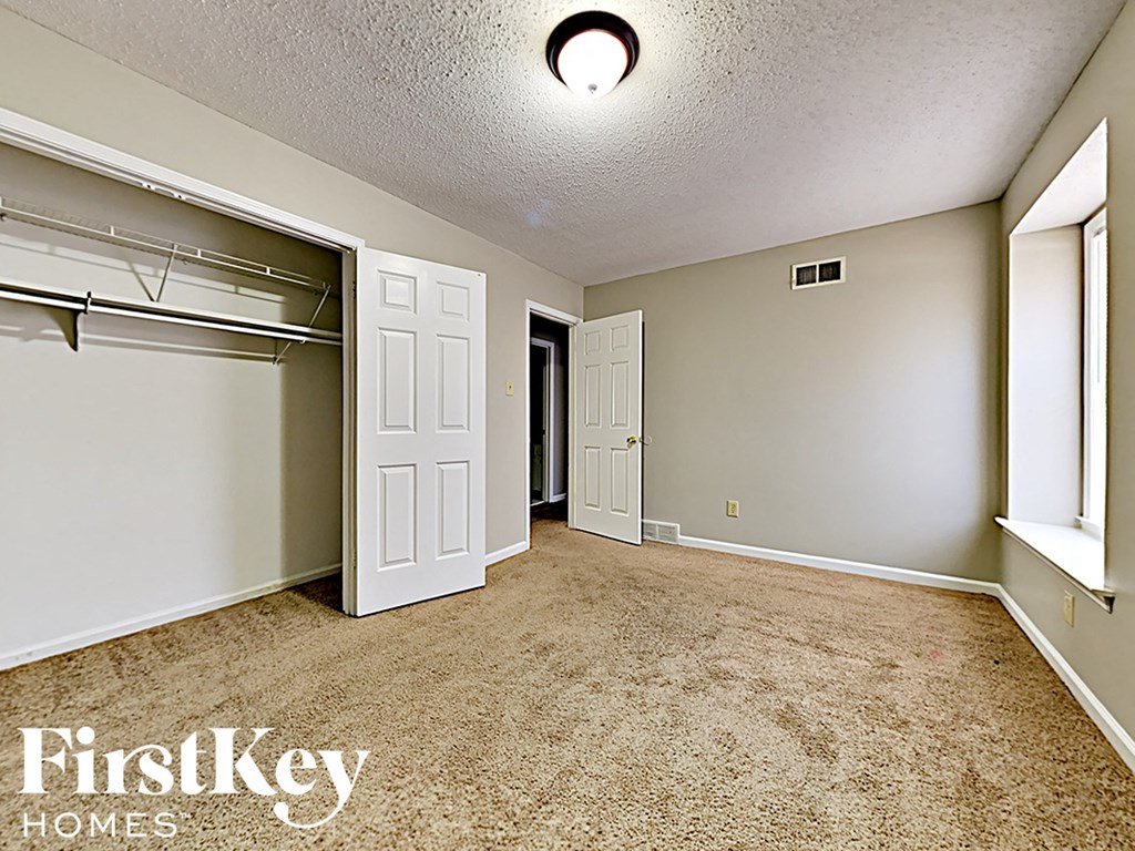 A bedroom with a carpeted floor and a closet with a white door.