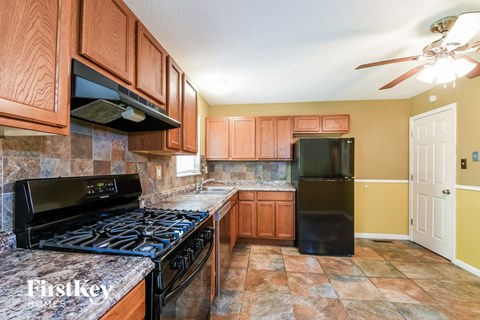 A kitchen with a black stove top oven and a black refrigerator.