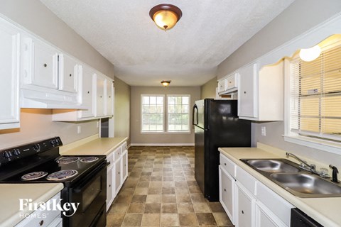 A kitchen with a black refrigerator and white cabinets.