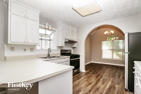A kitchen with white cabinets and a black fridge.