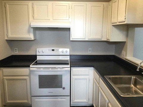 A white stove and oven in a kitchen with white cabinets.
