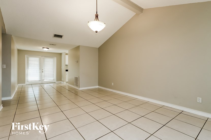 A spacious room with a tiled floor and a hanging light fixture.