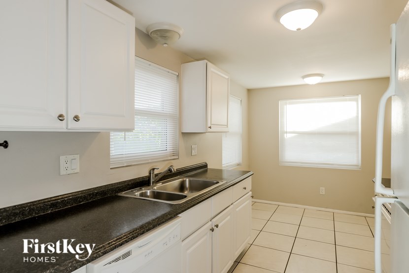 A kitchen with white cabinets and a black countertop.