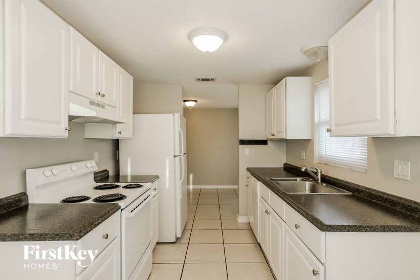 A kitchen with white cabinets and a black countertop.