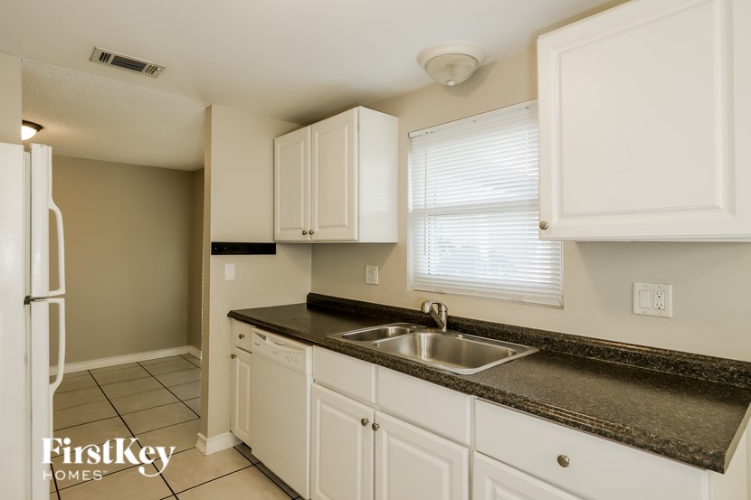 A kitchen with white cabinets and a black countertop.