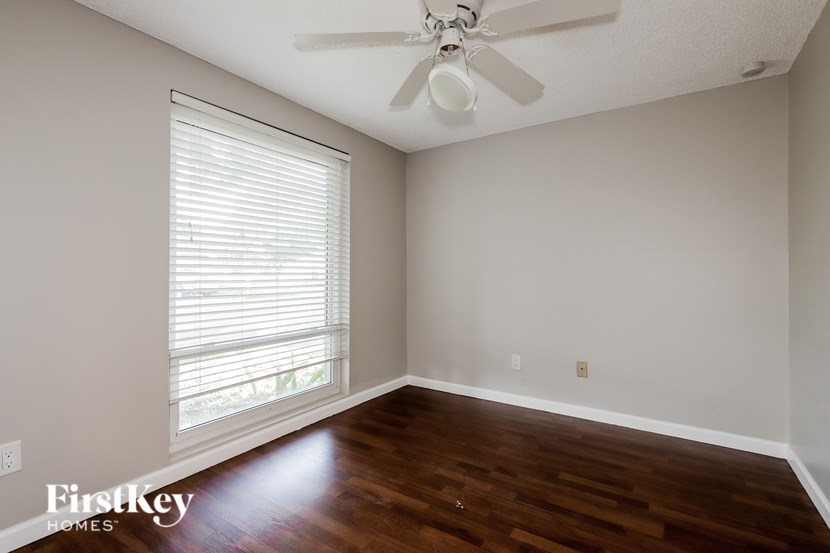 A room with a ceiling fan and a window with blinds.