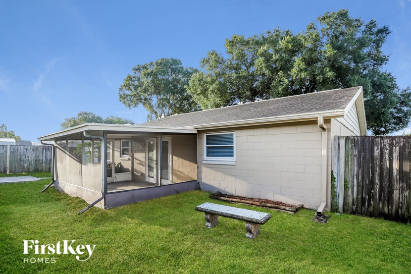 A house with a covered patio and a bench in the yard.