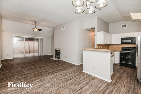 A kitchen with white cabinets and a wooden floor.