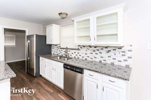 A kitchen with white cabinets and a granite countertop.