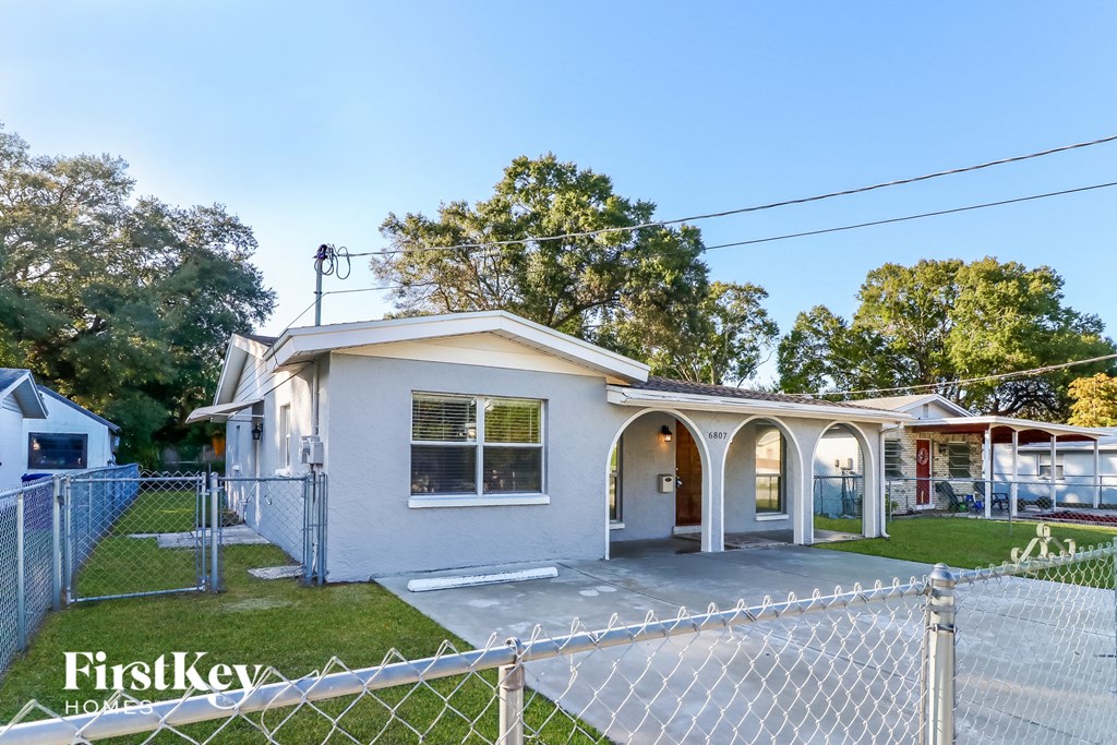 a small house with a fenced in yard and a chain link fence