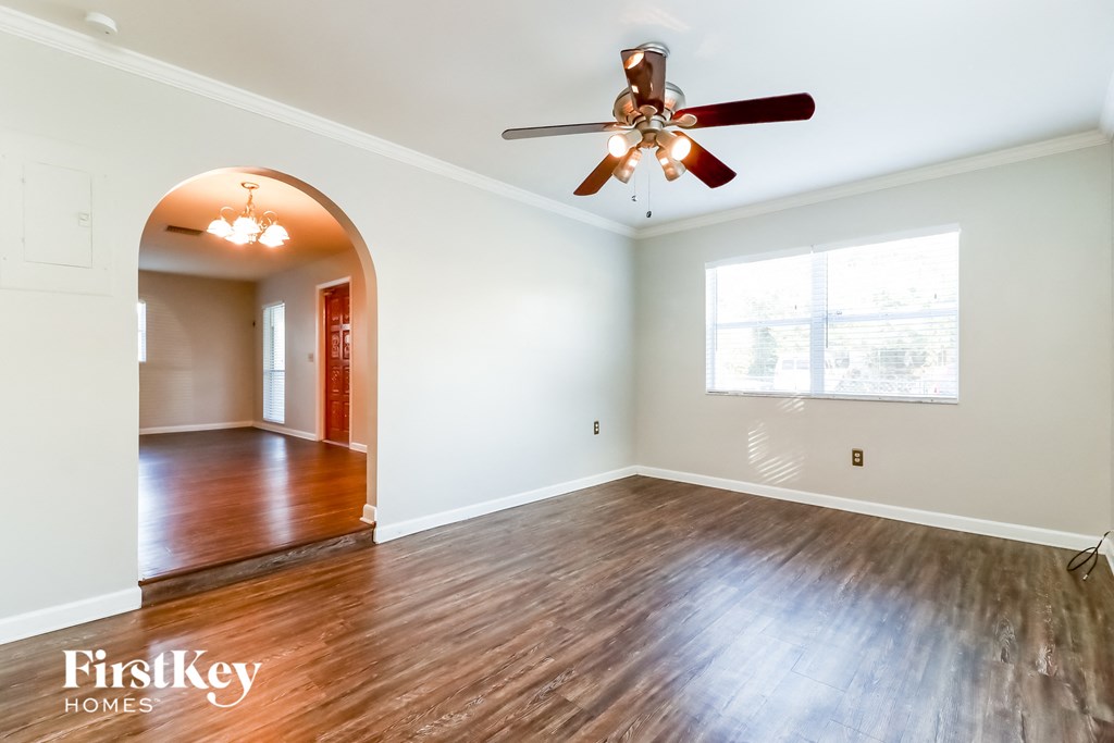 an empty living room with wood floors and a ceiling fan