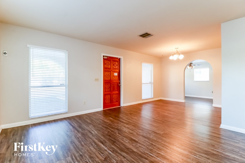 an empty living room with wood floors and a red door