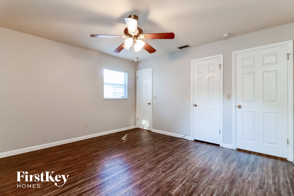 the living room of an empty house with wood flooring and a ceiling fan