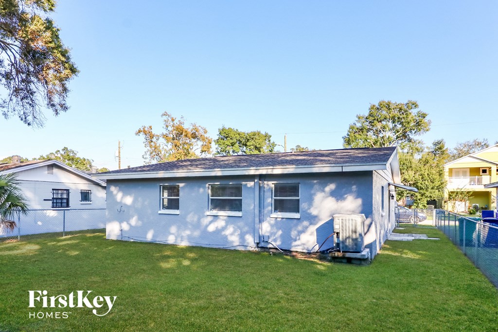 a small blue house with a yard and a fence