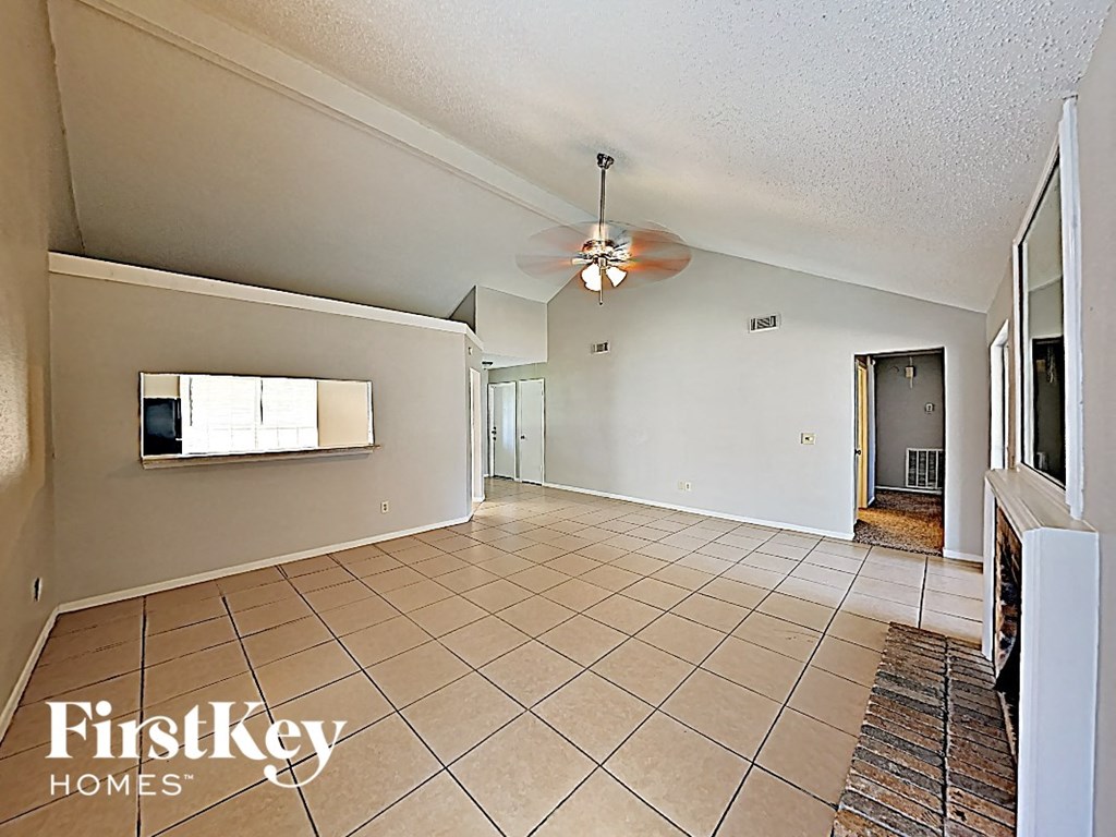 an empty living room with a ceiling fan and tiled floors