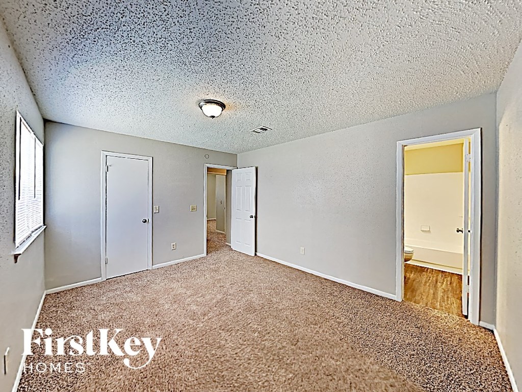 a spacious living room with carpet and a door to the hallway