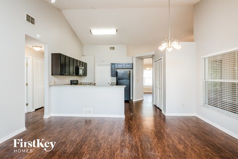 A spacious living room with wood flooring and a television mounted on the wall.