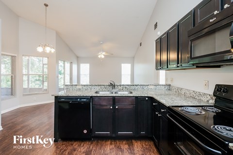A kitchen with black cabinets and a granite countertop.