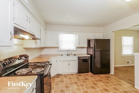 A kitchen with a black refrigerator and a stove with four burners.