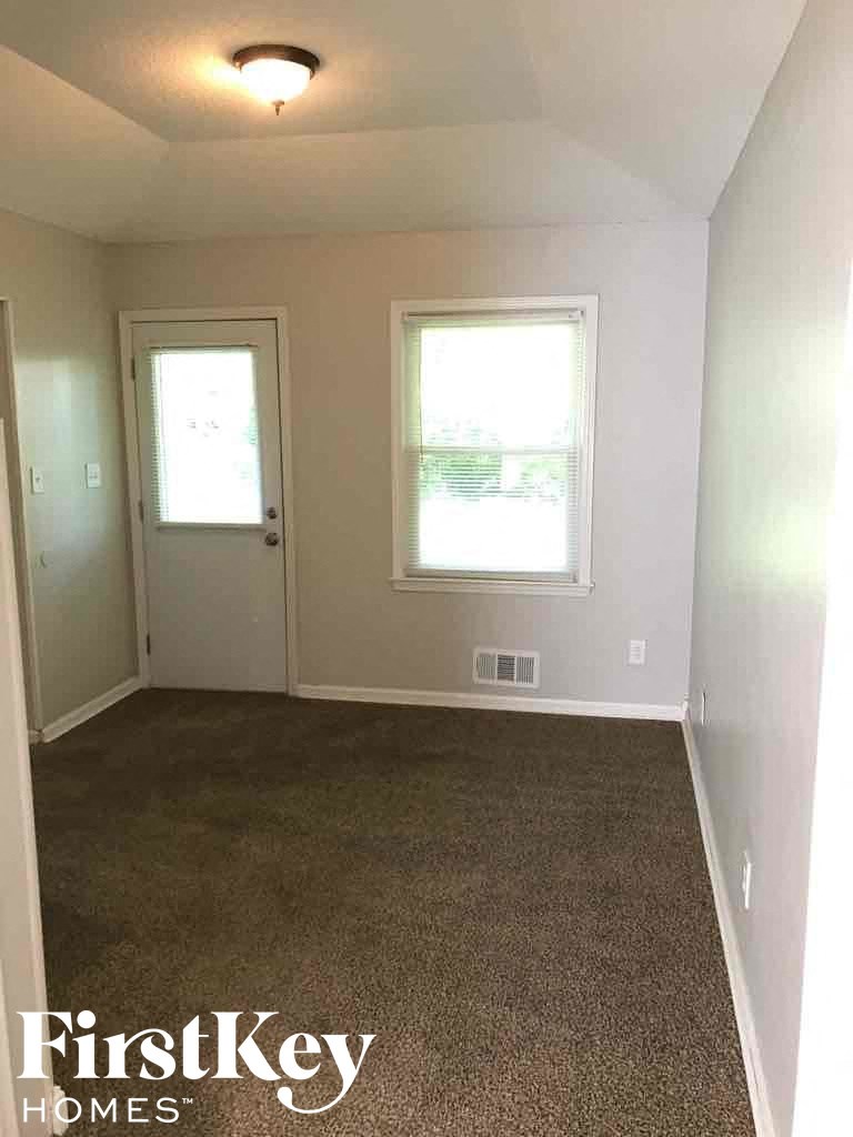 A room with a carpeted floor and two windows.