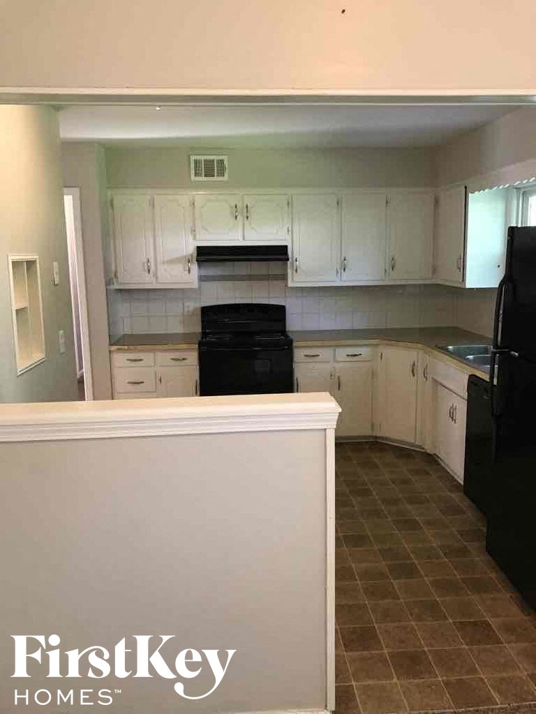 A kitchen with a black fridge and a white wall with the words "FirstKey Homes" on it.