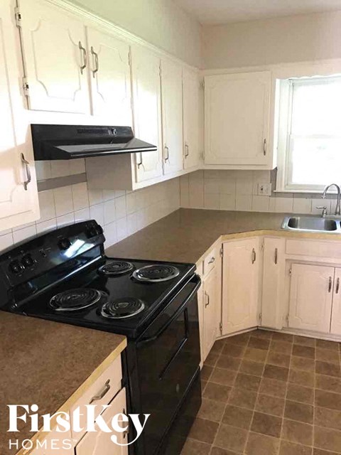 A kitchen with a black stove top oven and white cabinets.