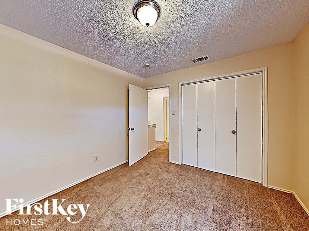 a bedroom with a closet and a carpeted floor