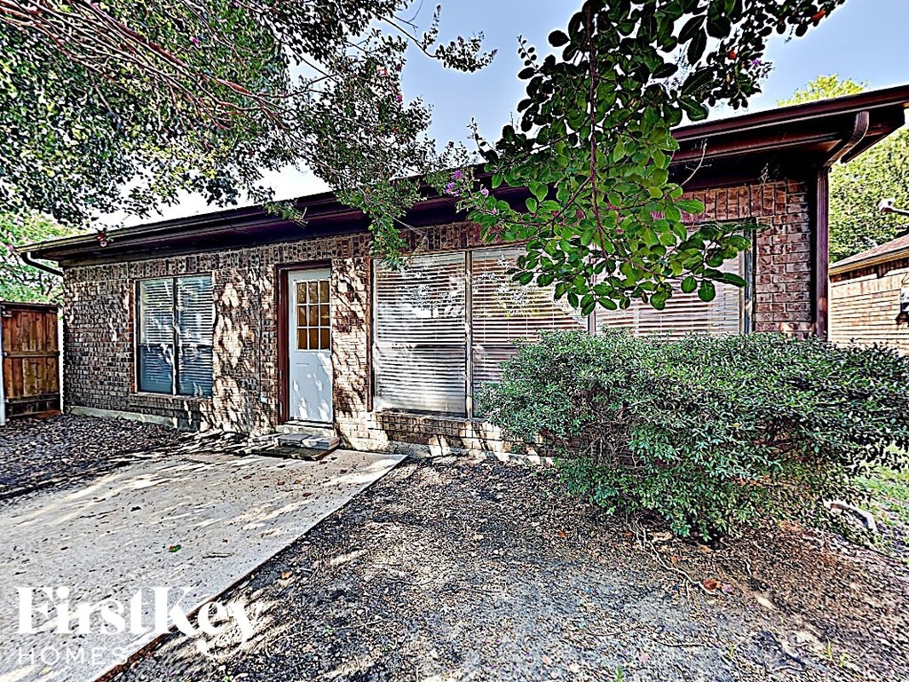 an old brick house with barred windows and a sidewalk
