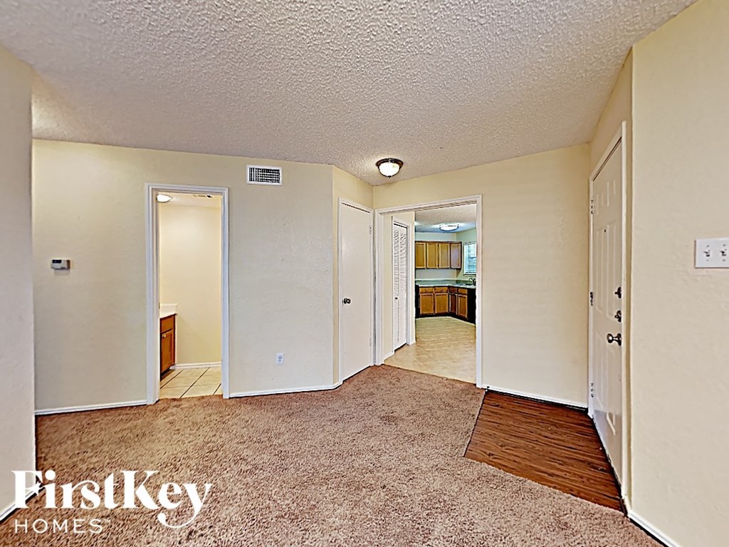 a hallway with a carpeted floor and a door to a bathroom