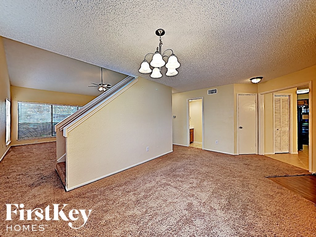 an empty living room with a staircase and a chandelier