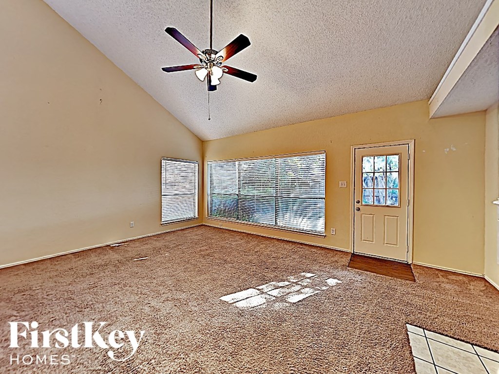 an empty living room with a ceiling fan and a window