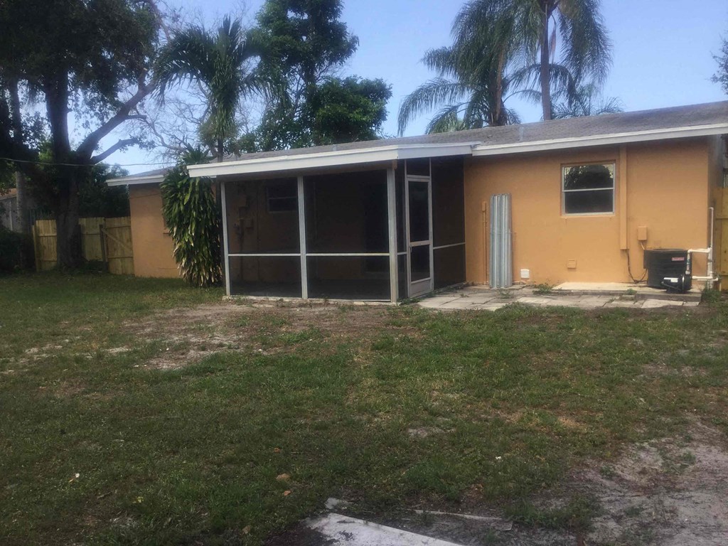 A yellow house with a white roof and a brown fence.
