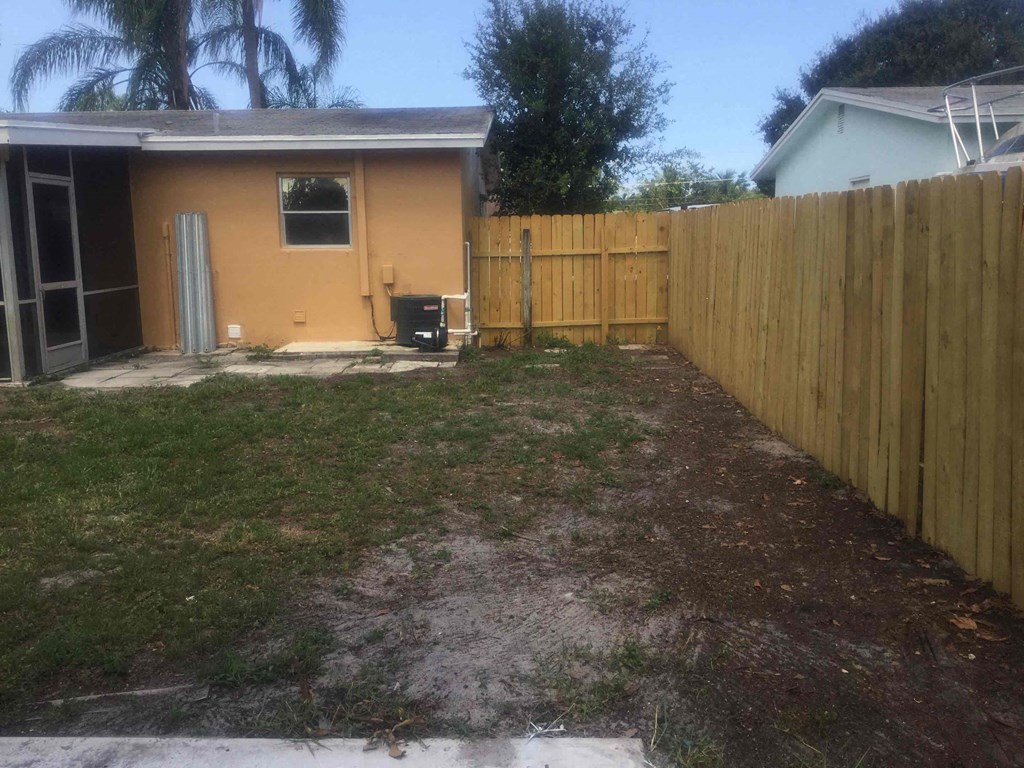 A backyard with a brown fence and a brown house.