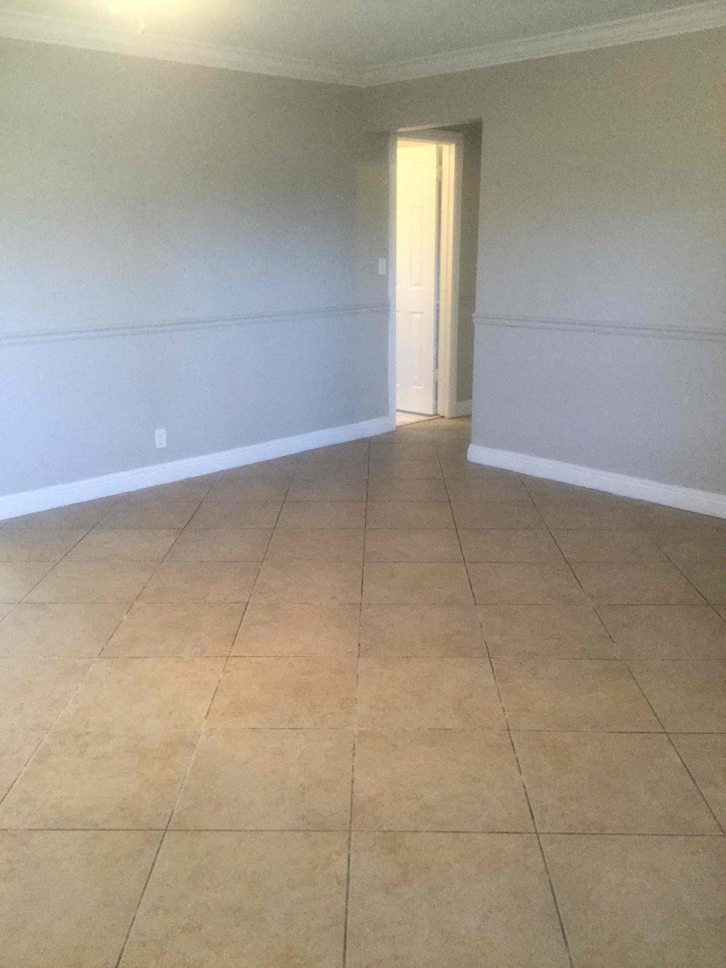 A room with a tile floor and a doorway leading to another room.