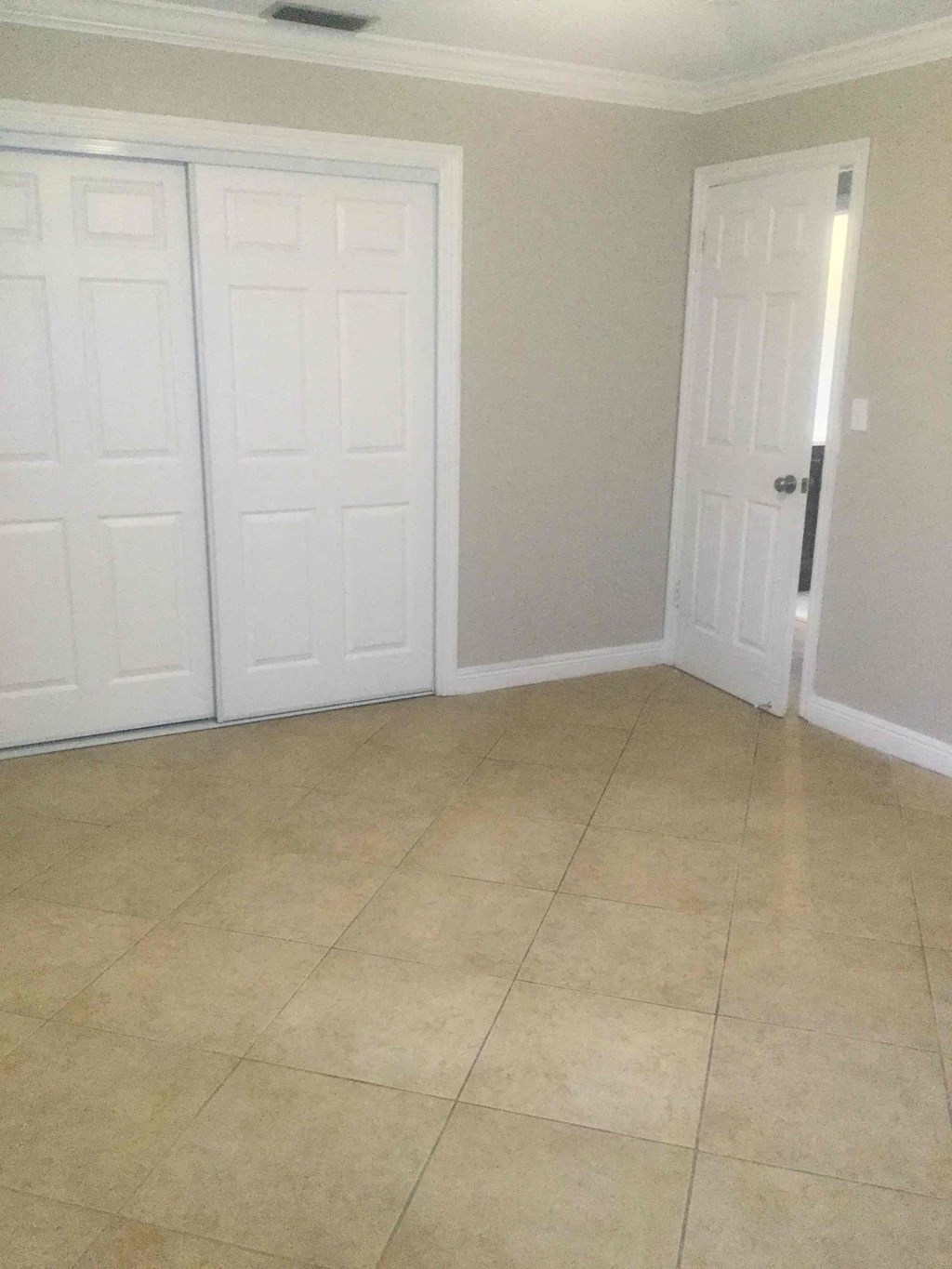 A room with a white door and a tiled floor.